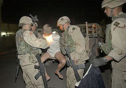 Soldados de la 4ª División del Ejército de EE UU trasladan a un detenido en la madrugada del martes en Tikrit.