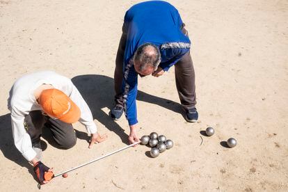 Dos jugadores miden la distancia entre el boliche y las bolas para comprobar cuál es la ganadora, en el parque de Aluche.