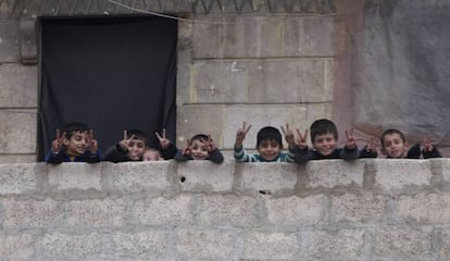 Varios niños hacen la señal de la victoria en los escombros de un edificio al este de Alepo, Siria.