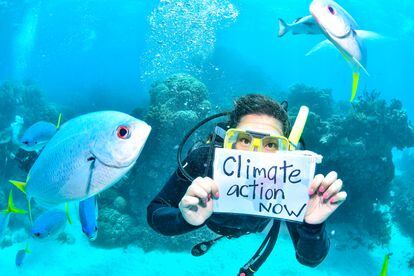 Mientras bucea, la activista Sandra Guzmán sostiene un cartel con la frase "Acción climática ya".