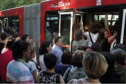 Madrileños haciendo cola, ayer, para entrar en los autobuses municipales repletos.