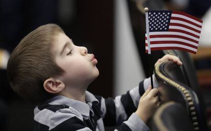 Un niño juega con una bandera de EE UU durante la ceremonia de naturalización de su madre. 