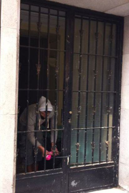 Uno de los 'okupas' de las viviendas cierra el candado del portal del número 11 de la calle de la Paz.