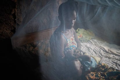 Una madre amamanta a su bebé bajo una mosquitera, en Sierra Leona.