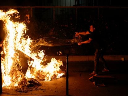 Un ciudadano echa agua a un contenedor en llamas, durante las protestas en París (Francia), el 30 de junio.