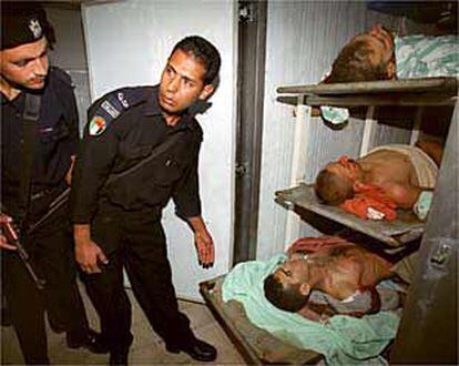 Policías palestinos observan tres cadáveres de jóvenes tiroteados por soldados Israelíes.