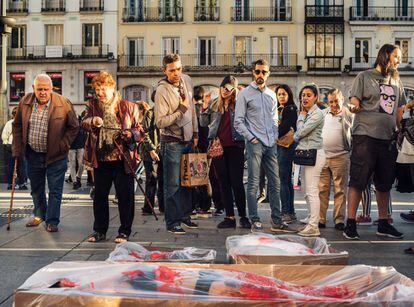Activistas en la Puerta del Sol de Madrid realizan una acción de "empaquetado", en la que fingen estar ensangrentados y envasados en plástico.