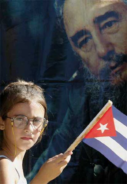Una niña sostiene una bandera junto a un retrato de Castro.