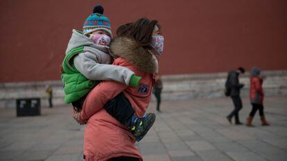 Una mujer y un bebé con máscaras a los pies de la Ciudad Prohibida de Pekín.