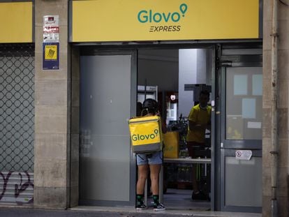 Rider de Glovo frente a un supermercado exprés de la compañía de reparto a domicilio en Barcelona.