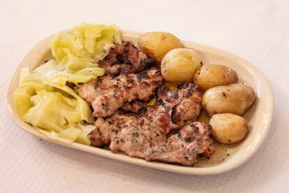 Plato del día de secretos de cerdo negro con patatas y repollo.