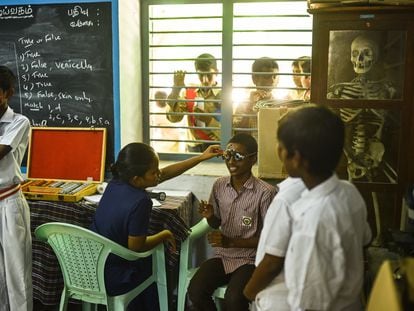 Un médico indio examina el ojo de un escolar durante una campaña de revisión ocular tras el aumento de casos de conjuntivitis vírica u ojo de Madrás, en un colegio, en Chennai (India).