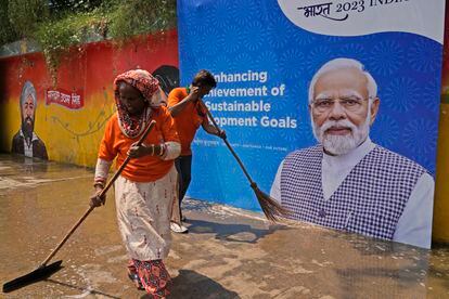 Trabajadores municipales limpiaban una calle junto a un cartel del primer ministro de la India, Narendra Modi, el jueves en Nueva Delhi.