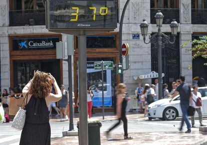 En muchos lugares de las 35 provincias afectadas por la ola de calor las temperaturas alcanzarán los 38-40 grados y no descenderán de los 22 por la noche. En la imagen, una mujer toma una fotografía de un termómetro situado en la plaza del Ayuntamiento de Valencia.