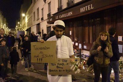 Un musulmán muestra un cartel que dice "el terrorismo en es islam" en el lugar de uno de los atentados.