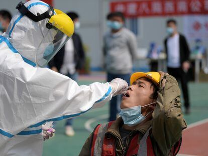 Personal sanitario efectúa la prueba del coronavirus a un trabajador en Wuhan