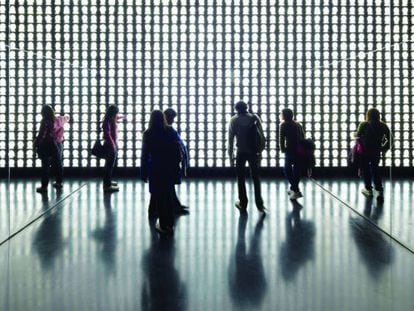 Varios visitantes observan la obra de Alfredo Jaar.