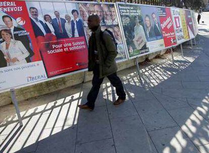 Un hombre pasa delante de una pared repleta de carteles electorales ayer en Ginebra.
