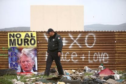 A Mexican federal police officer walks in front of a poster protesting Donald Trump's wall in Tijuana, Mexico, on March 13.