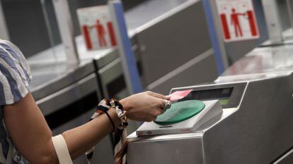 Una mujer pasa su billete en el torno del Metro Plaza de España, en Madrid (España).