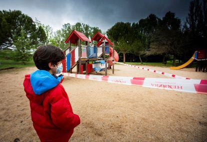 Un niño mira con nostalgia el parque donde suele jugar, ahora precintado, en Aranda de Duero (Burgos).