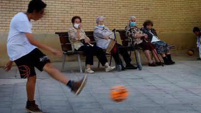 Abuelas en un parque de Terrassa usan mascarillas mientras los niños juegan con la pelota.