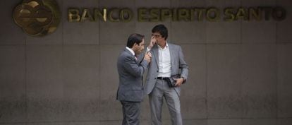 Dos hombres charlan junto a la fachada del Banco Espírito Santo en Lisboa.