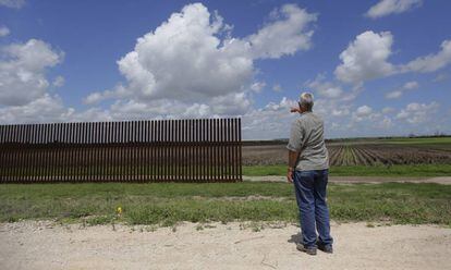 Un hombre se&ntilde;ala un tramo de la valla fronteriza en Brownsville (Texas) en una imagen de 2005