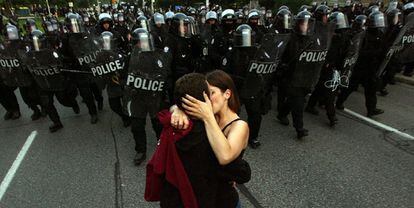 Una pareja se besa ante un pelotón policial que intentaba contener los disturbios en las calles de Toronto.