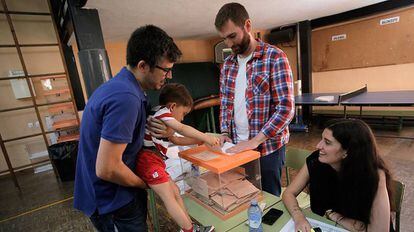 Un ni&ntilde;o mete en la urna el voto de su padre en un colegio de Madrid.