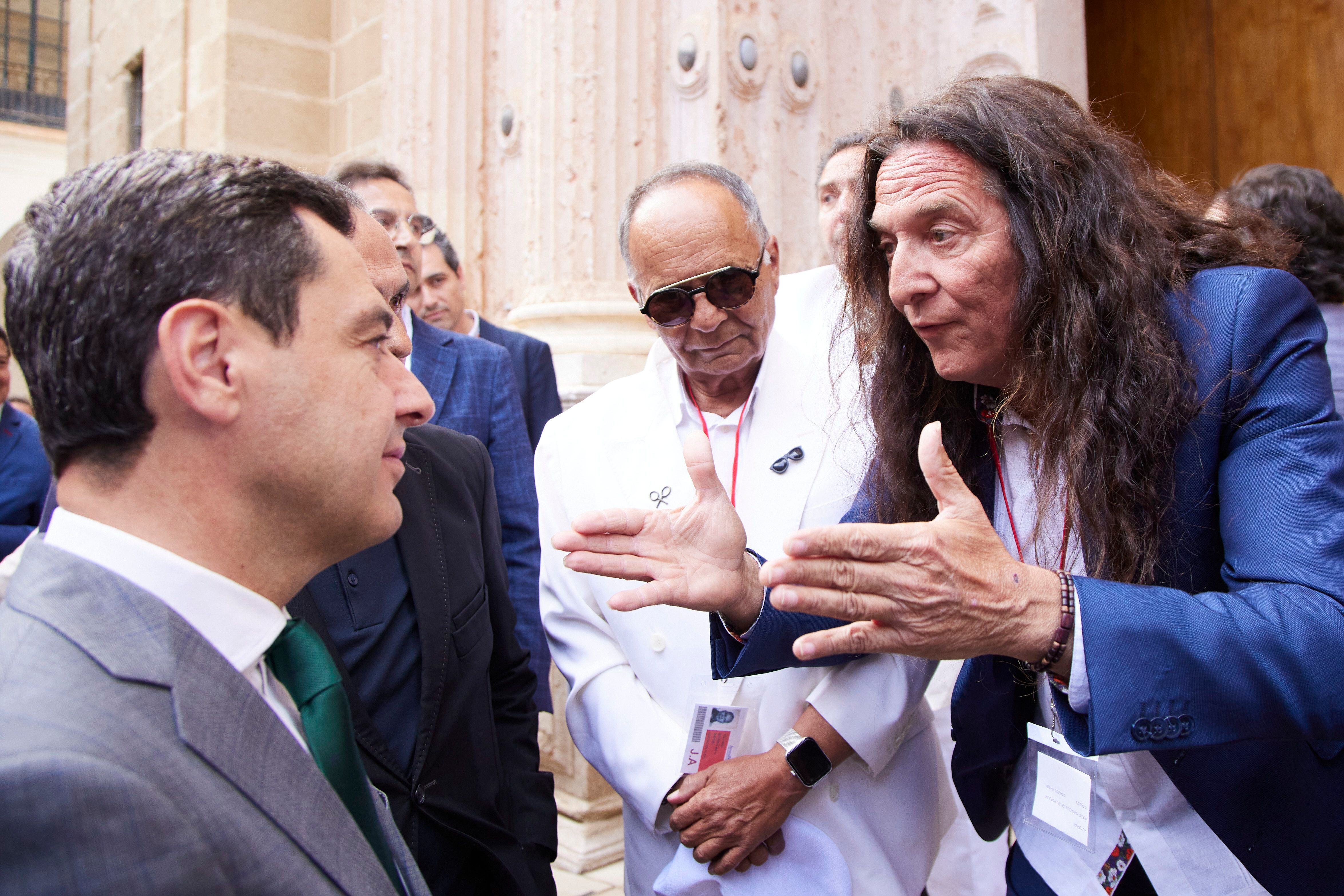 El presidente de la Junta de Andalucía, Juan Manuel Moreno (izquierda), dialoga con el cantaor Tomatito tras la aprobación de la ley.