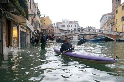 Un hombre cruza la calle inundada en kayak durante el período de temporada alta en Venecia, el 15 de noviembre de 2019.