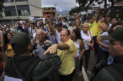 Un grupo de venezolanos grita consignas mientras que el gobernador del estado, del partido gobernante deposita su voto durante las elecciones legislativas, en San Cristóbal, Estado Táchira.