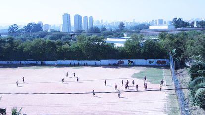 Moradores de la São Remo juegan un partido en el campo de fútbol de la comunidad. Al fondo, separada de la favela solo por un muro de cemento, la Universidad de Sâo Paulo, posicionada entre las mayores instituciones de enseñanza superior en América Latina. 
