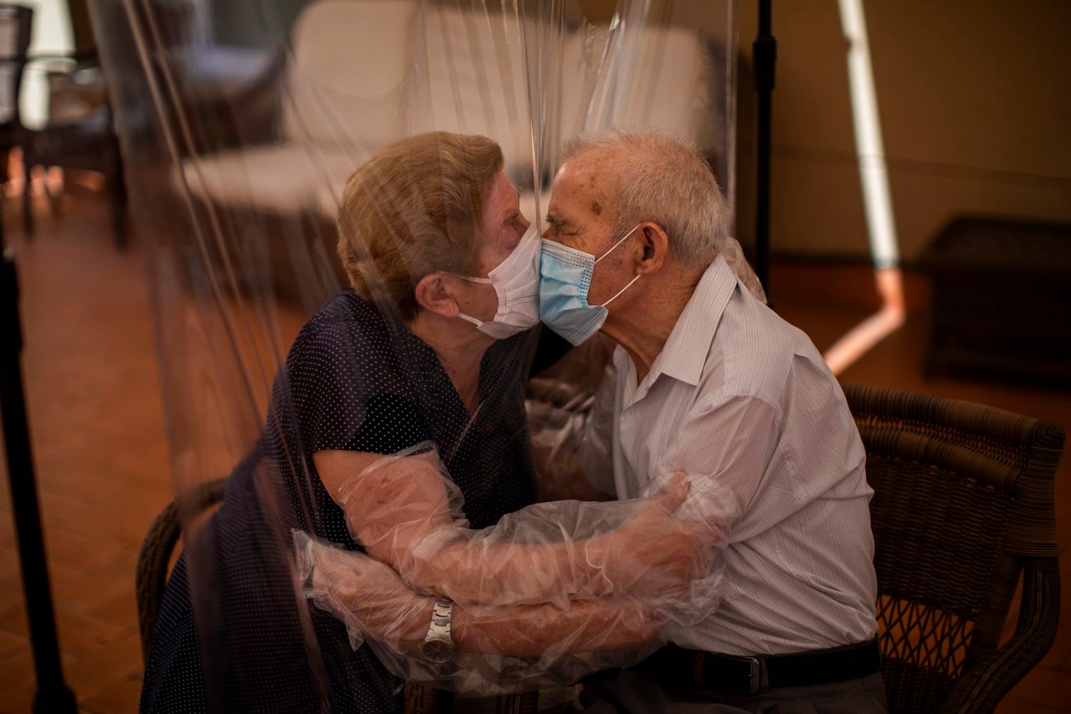Agustina Cañamero, de 81 años, y Pascual Pérez, de 84, se abrazan y besan a través de una pantalla de película plástica para evitar contraer el nuevo coronavirus en un asilo de ancianos en Barcelona, España, el lunes 22 de junio de 2020,en el centro de ancianos Ballesol Fabra i Puig.