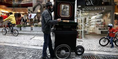 Un hombre toca el organillo en una calle comercial de Atenas. 