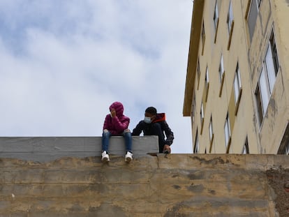 Dos niños sentados sobre un muro en la nave de primera acogida del polígono del Tarajal, a 20 de mayo de 2021, en Ceuta (España). Durante los últimos tres días Ceuta ha recibido 8.000 ciudadanos marroquíes, de los cuales 5.600 ya han sido expulsados o retornados voluntariamente al Reino alauita.