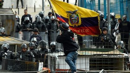 Un manifestante ondea una bandera de Ecuador delante de la Asamblea Nacional rodeada de policía este sábado.