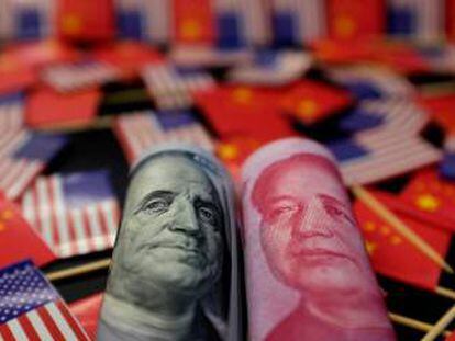 Billetes de d&oacute;lar y yuan entre banderas de EE UU y China.