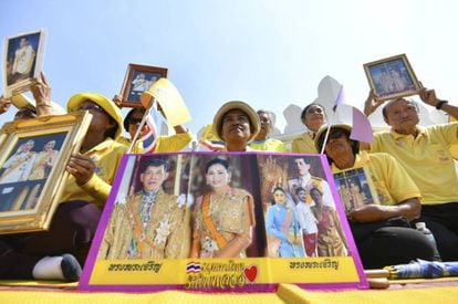 Varios ciudadanos posan con retratos del rey Rama X y la reina Suthida de Tailandia en la ceremonia de coronación. 