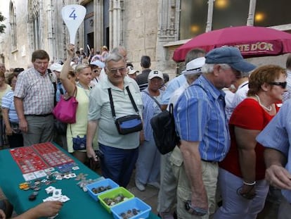 Un grupo de cruceristas pasa frente a un puesto de numism&aacute;tica tras visitar la Lonja de Valencia.