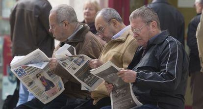 Tres jubilados leen la prensa en una calle de Málaga.