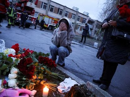 Una mujer llora tras depositar unas flores cerca del lugar donde se estrelló horas antes un helicóptero, en Brovary a las afueras de Kiev.
