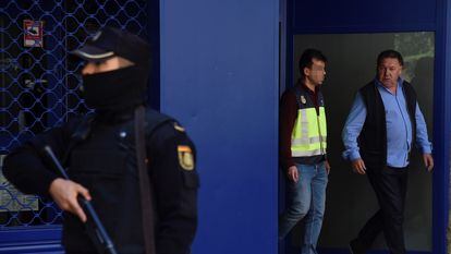 El presidente del Huesca, Agustín Lasaosa junto a un policía a su salida de las oficinas del club tras ser detenido durante la "Operación Oikos" en mayo de 2019.