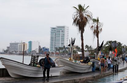 El pronóstico señala que el fenómeno avanzará tierra adentro hasta el Estado de Durango en los próximos tres días. En la imagen, un hombre camina junto a embarcaciones almacenadas en tierra antes de la llegada de 'Orlene' a Mazatlán. 