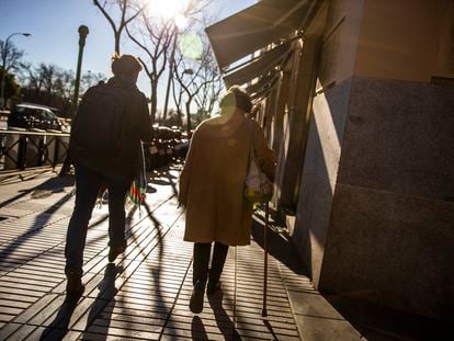 Una mujer mayor paseando de espaldas con un bastón por la calle Alcalá, en Madrid.
