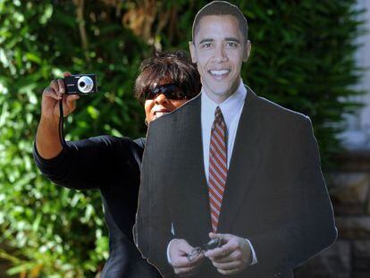 Una partidaria de Obama toma fotos, tras una figura de cart&oacute;n del presidente. 