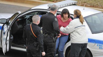 Agentes policiales introducen a la detenida en un coche patrulla.