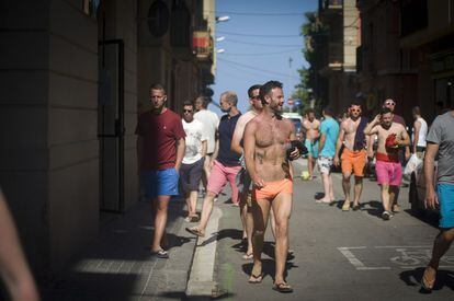 Un grup de nois passeja per la Barceloneta amb banyador.