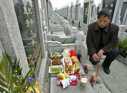 Un hombre se arrodilla ante la tumba de un familiar en un cementerio de Shanghai en 2004.